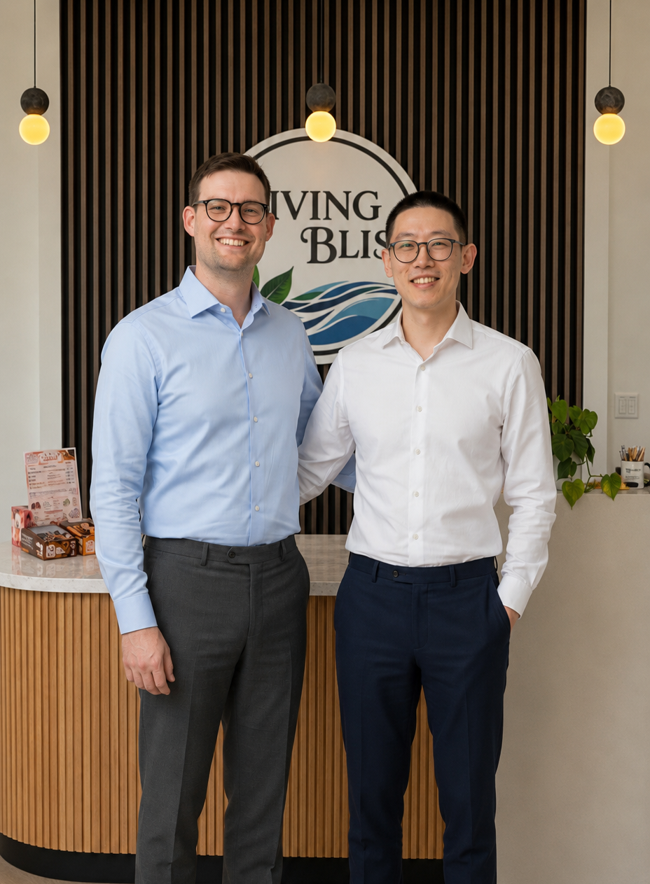 Two men standing together in front of a branded wall with 'Living Bliss' logo.